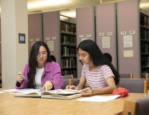 Students sitting at table discussing textbook